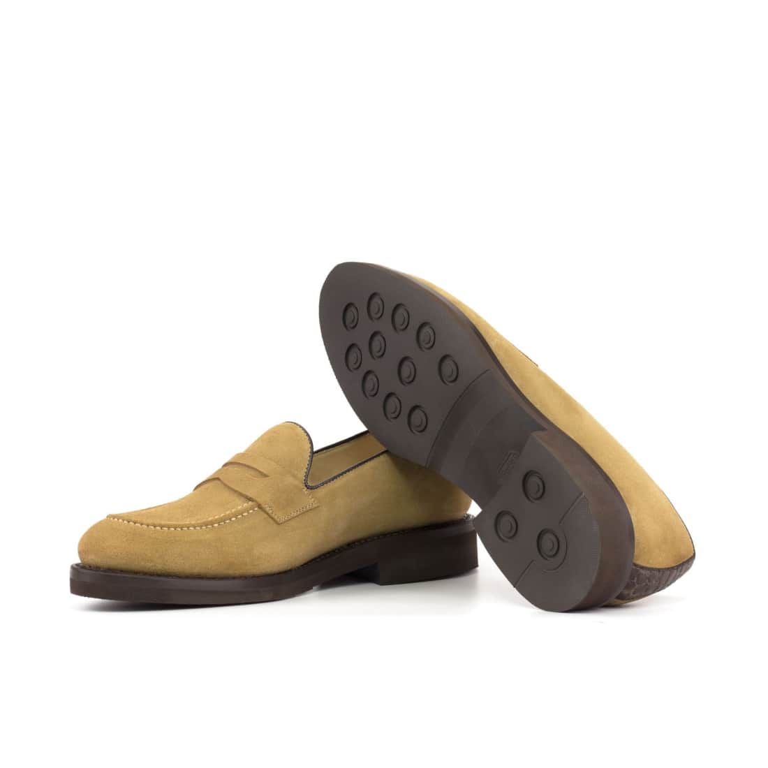 Mocassins penny en daim beige, l’un couché qui montre sa semelle en caoutchouc marron à plots ronds