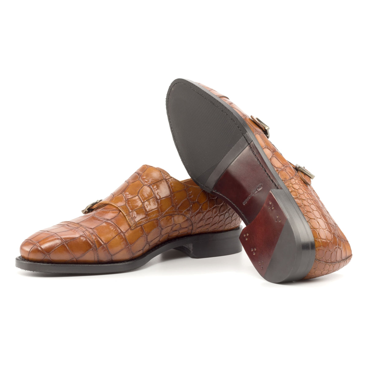 Chaussure double boucle en cuir croco cognac : une chaussure debout, l’autre couchée montre sa semelle