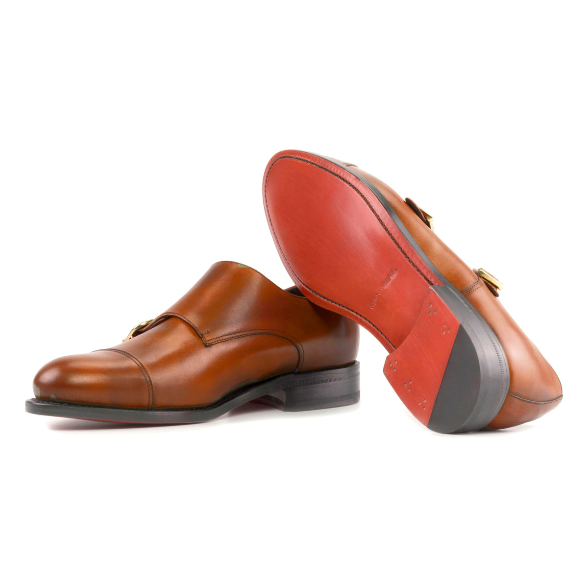 Chaussure double boucle en cuir teinté main cognac : une chaussure debout, l’autre couchée montre sa semelle