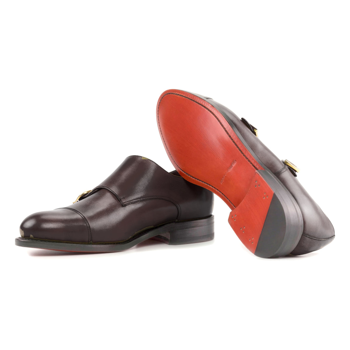 Chaussure double boucle en cuir teinté main marron foncé : une chaussure debout, l’autre couchée montre sa semelle