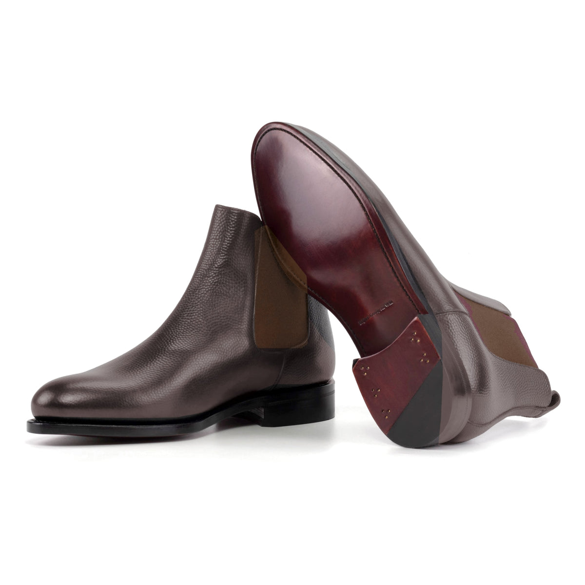 Chelsea Boots en cuir grainé marron foncé, semelle cuir : une bottine debout, l’autre couchée montre sa semelle