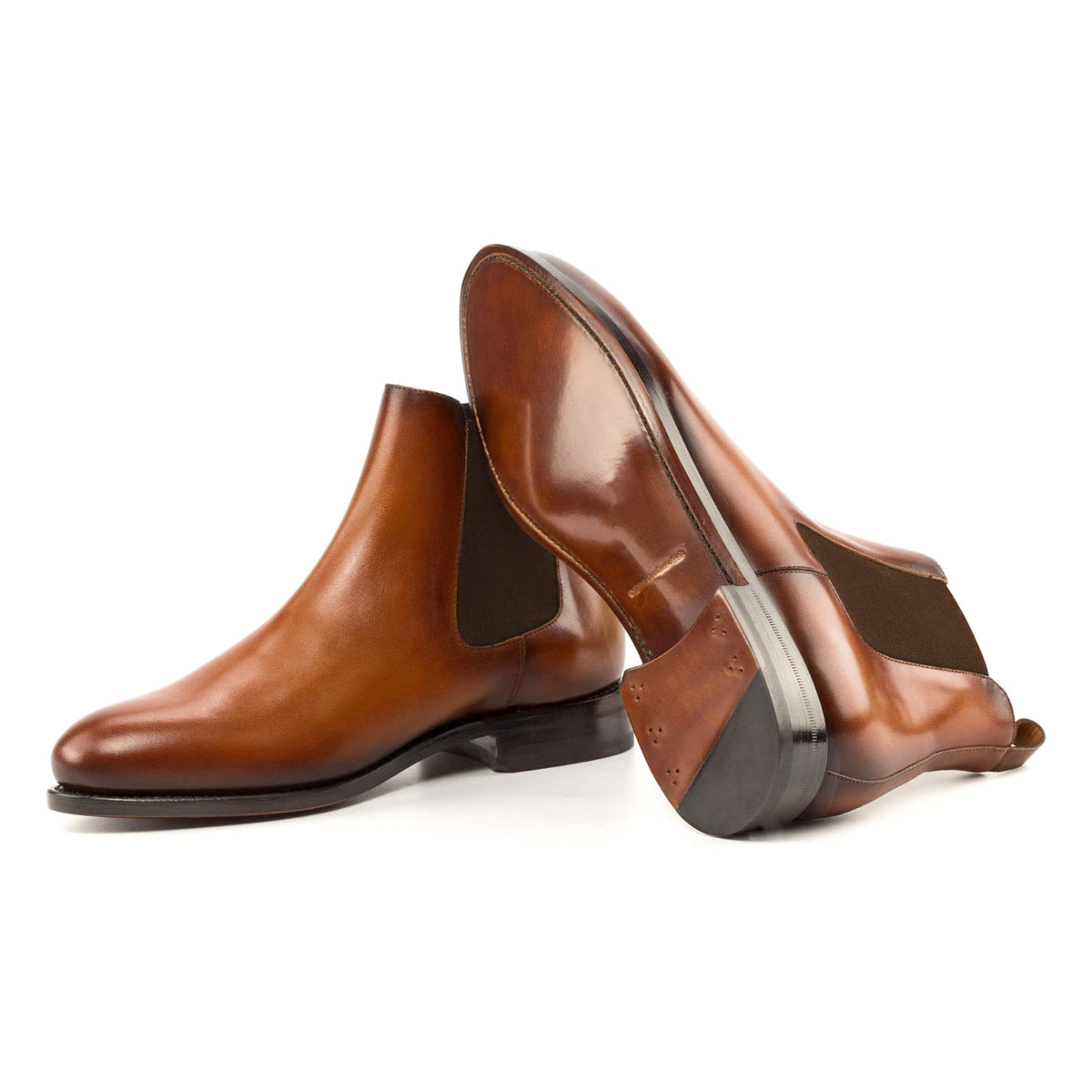 Chelsea Boots en cuir teinté main cognac, semelle cuir : une bottine debout, l’autre couchée montre sa semelle