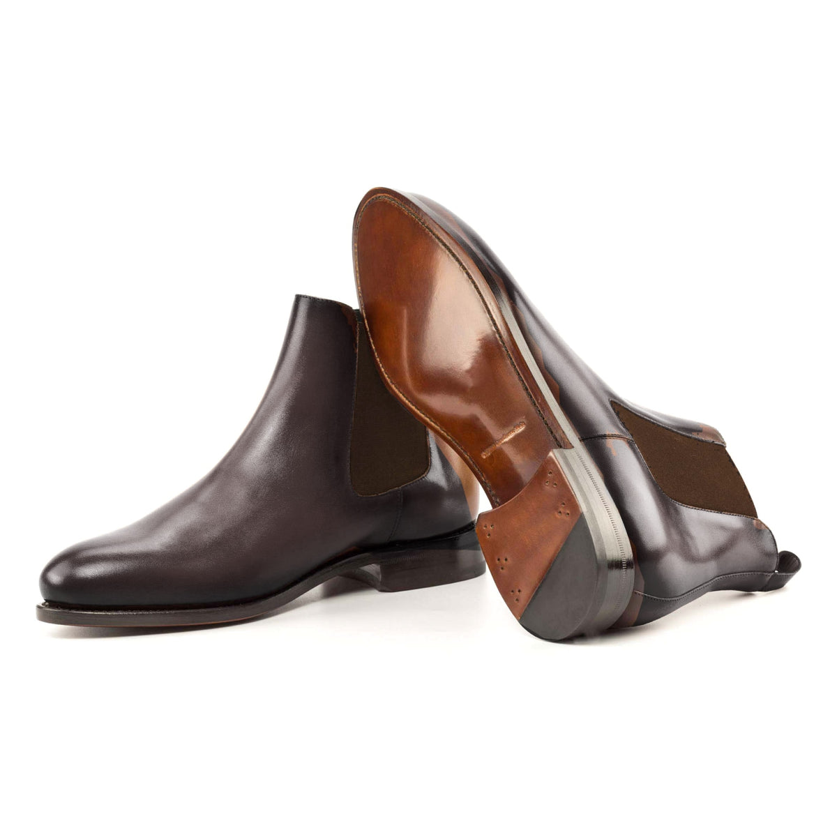 Chelsea Boots en cuir teinté main marron foncé, semelle cuir : une bottine debout, l’autre couchée montre sa semelle