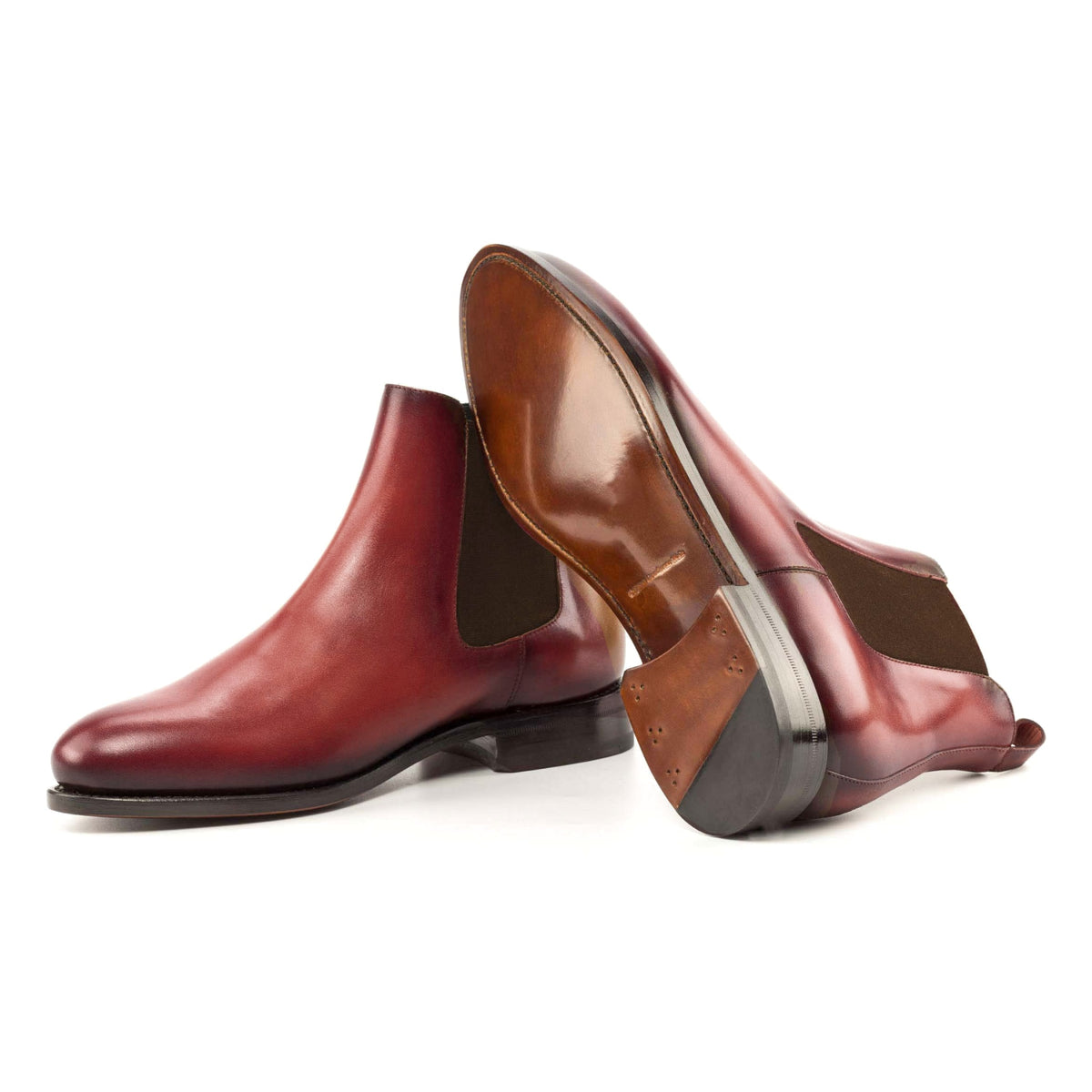 Chelsea Boots en cuir teinté main rouge, semelle cuir : une bottine debout, l’autre couchée montre sa semelle