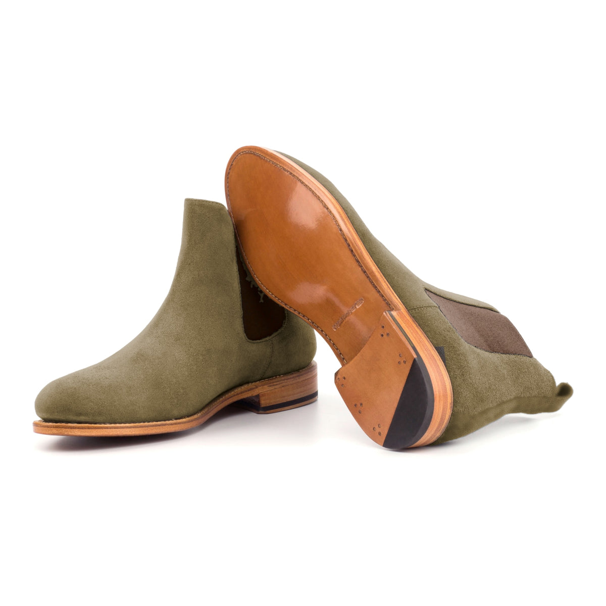 Chelsea Boots en daim kaki, semelle cuir : une bottine debout, l’autre couchée montre sa semelle