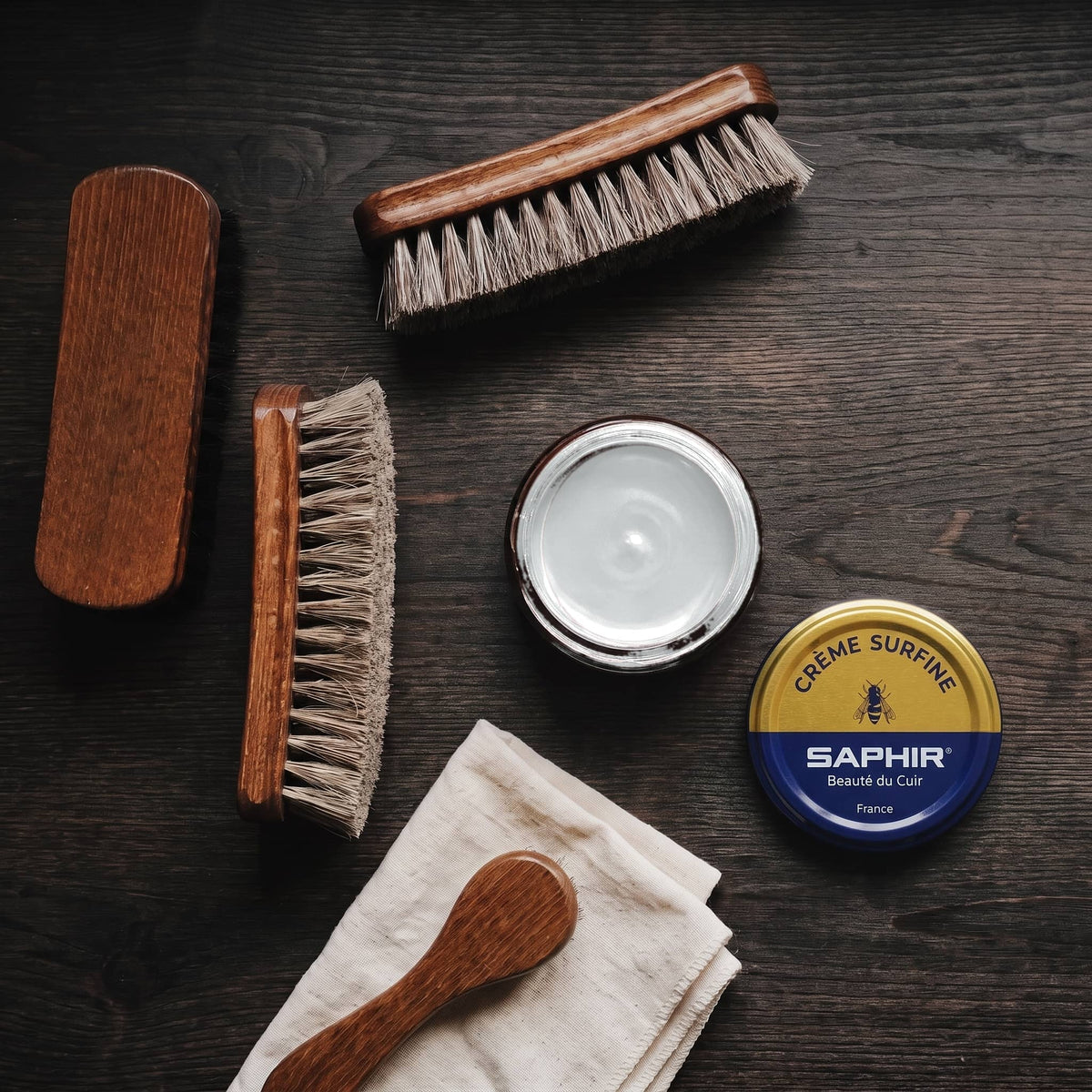Crème Surfine Saphir Argent en pot ouvert, avec des brosses en crin et une chamoisine, vue de dessus