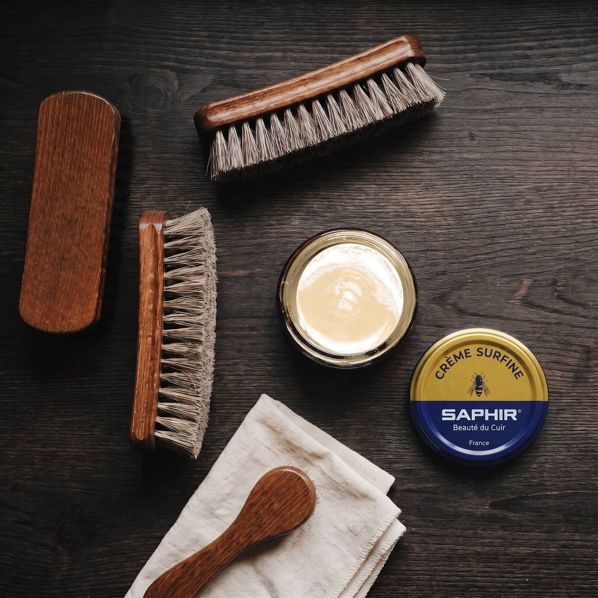 Crème Surfine Saphir Beige en pot ouvert, avec des brosses en crin et une chamoisine, vue de dessus