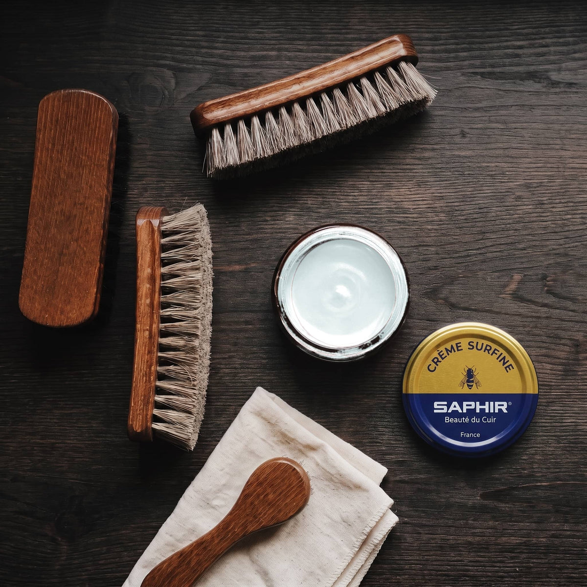 Crème Surfine Saphir Bleu pâle en pot ouvert, avec des brosses en crin et une chamoisine, vue de dessus