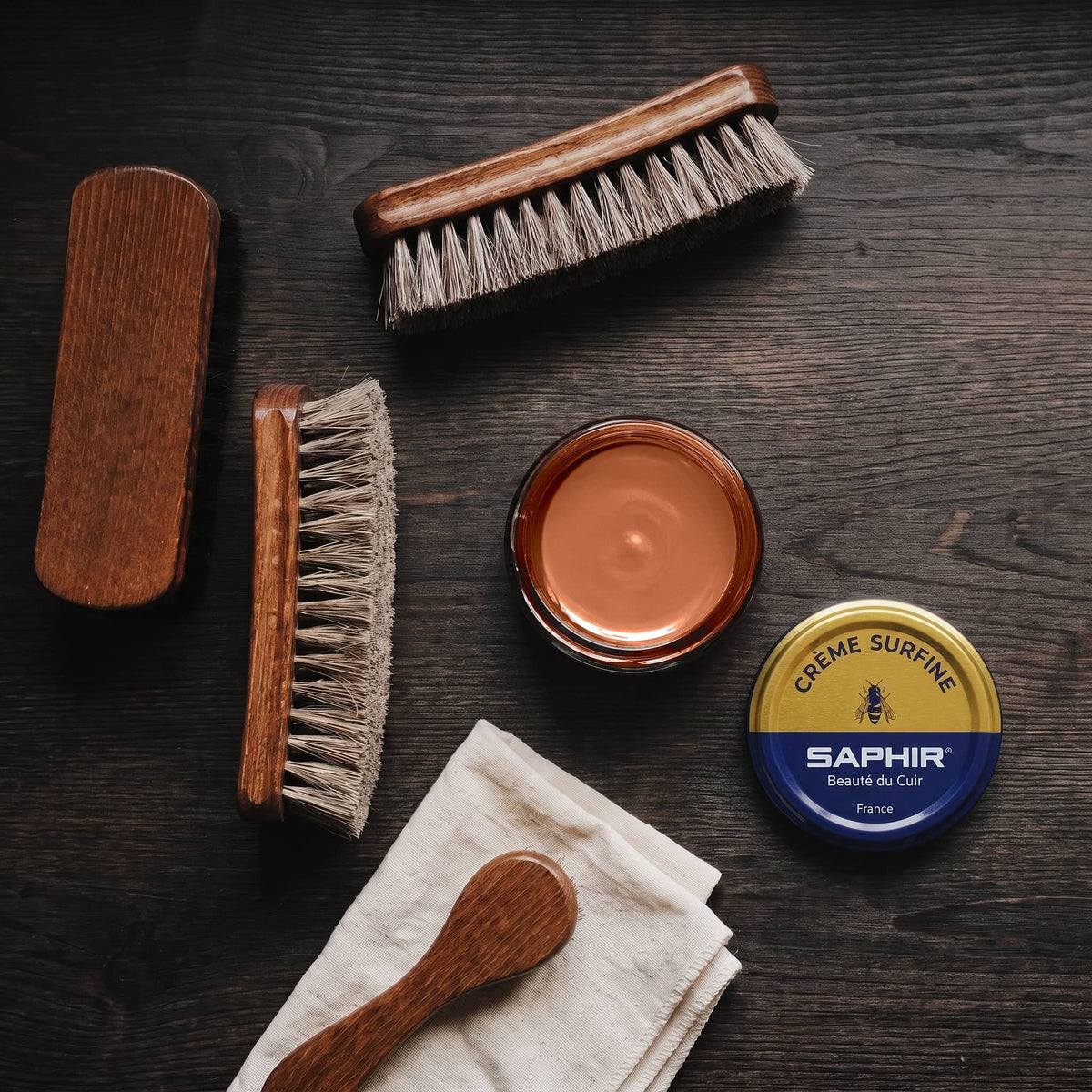 Crème Surfine Saphir Brun Cuivré en pot ouvert, avec des brosses en crin et une chamoisine, vue de dessus