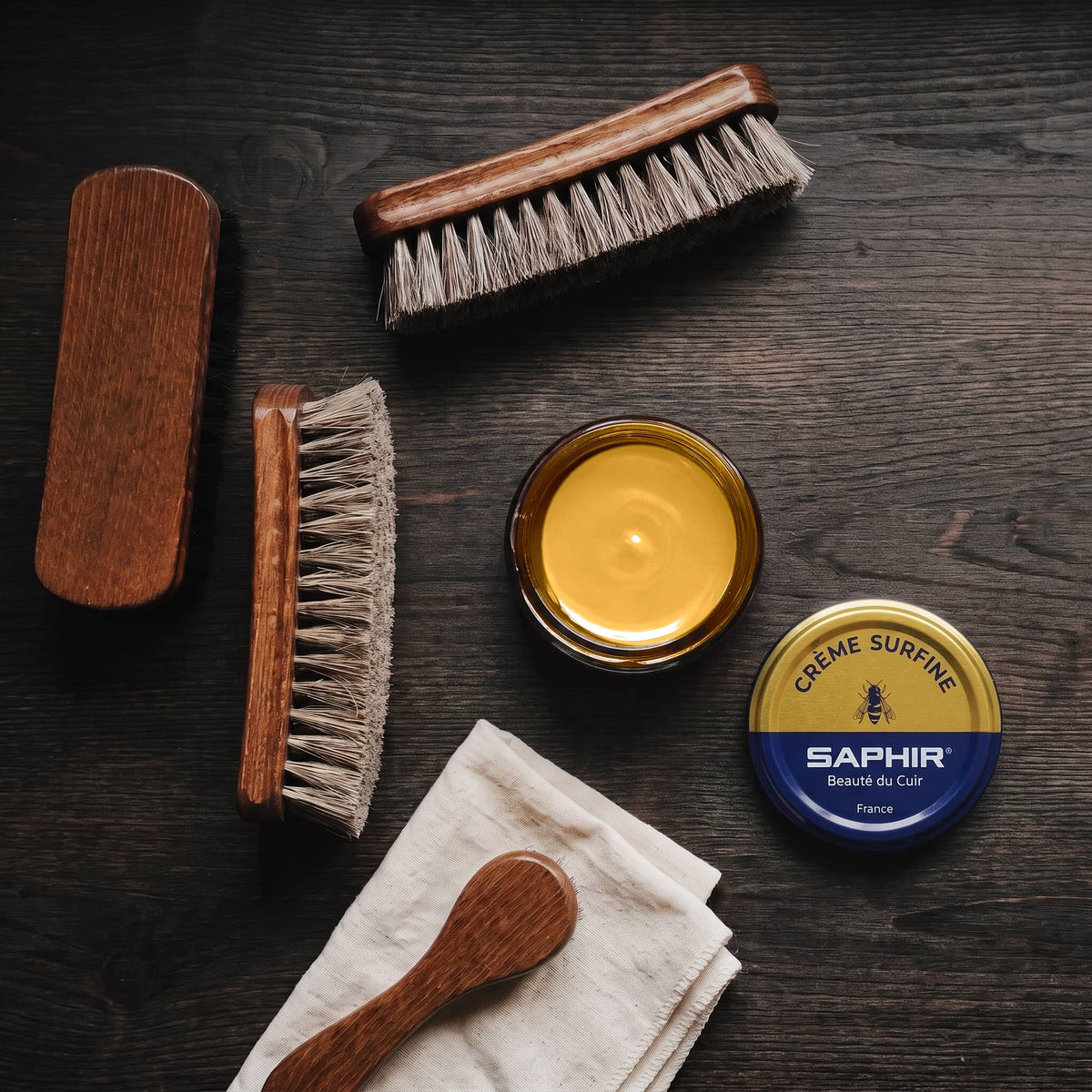Crème Surfine Saphir Caramel en pot ouvert, avec des brosses en crin et une chamoisine, vue de dessus
