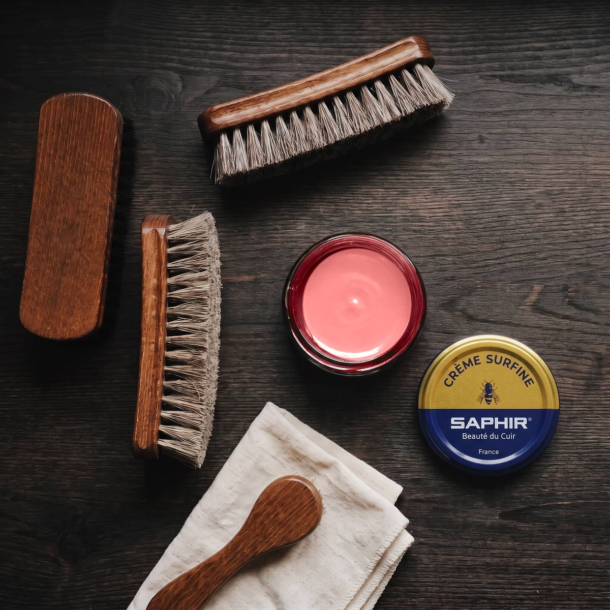 Crème Surfine Saphir Corail en pot ouvert, avec des brosses en crin et une chamoisine, vue de dessus