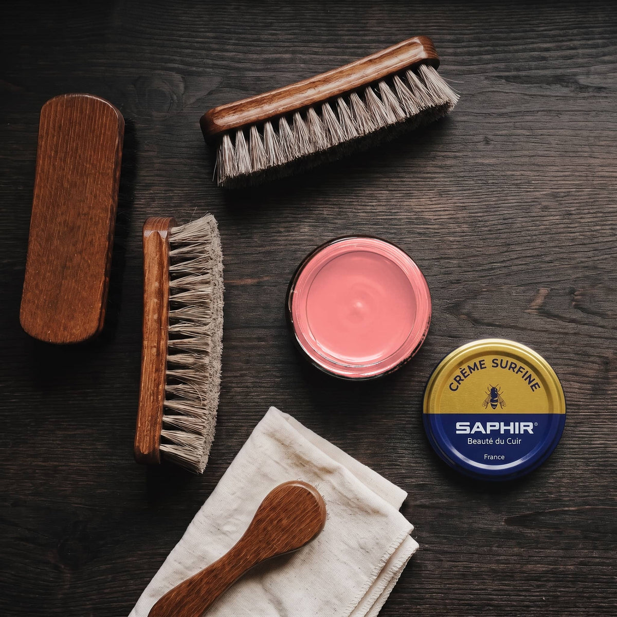 Crème Surfine Saphir Corail en pot ouvert, avec des brosses en crin et une chamoisine, vue de dessus