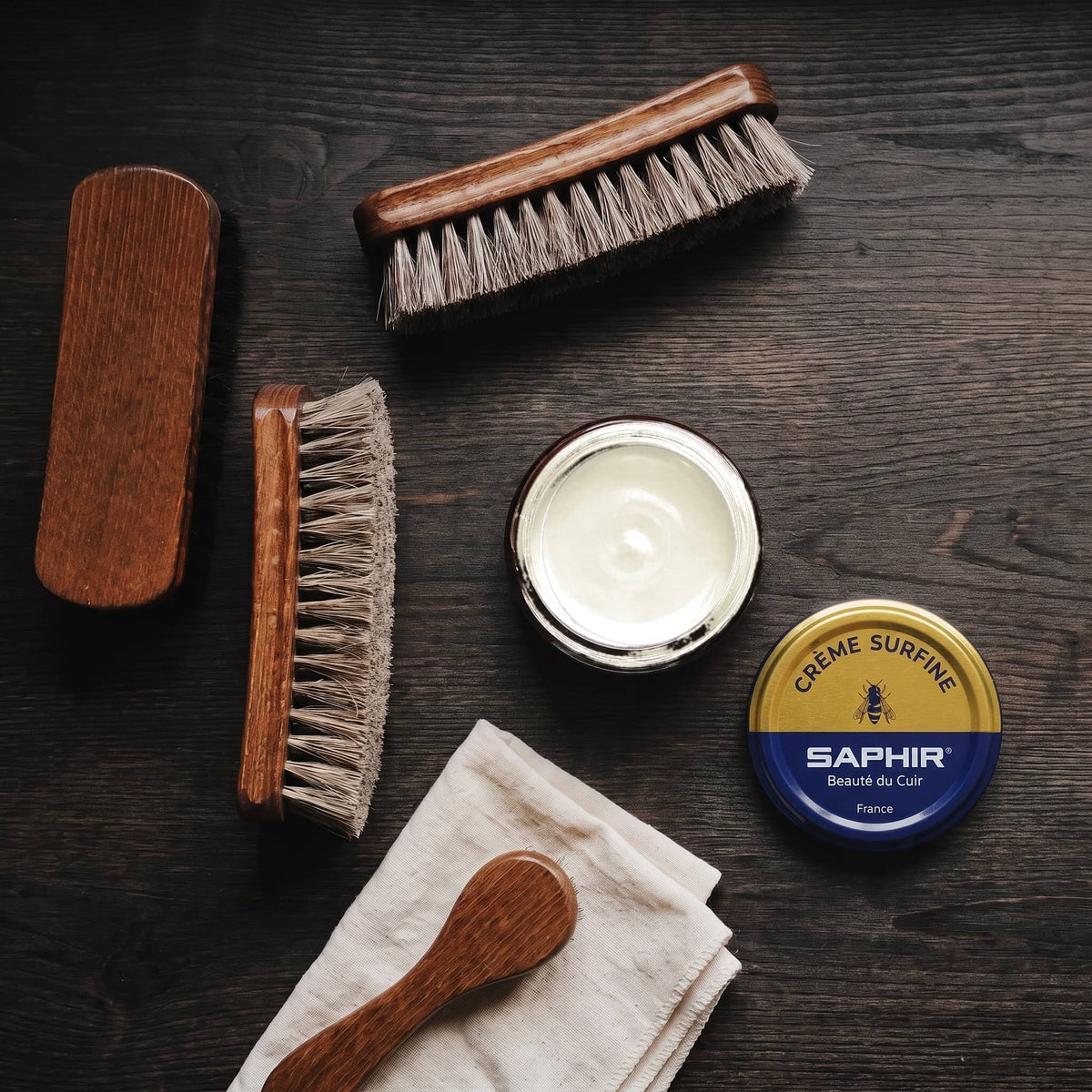 Crème Surfine Saphir Crème en pot ouvert, avec des brosses en crin et une chamoisine, vue de dessus