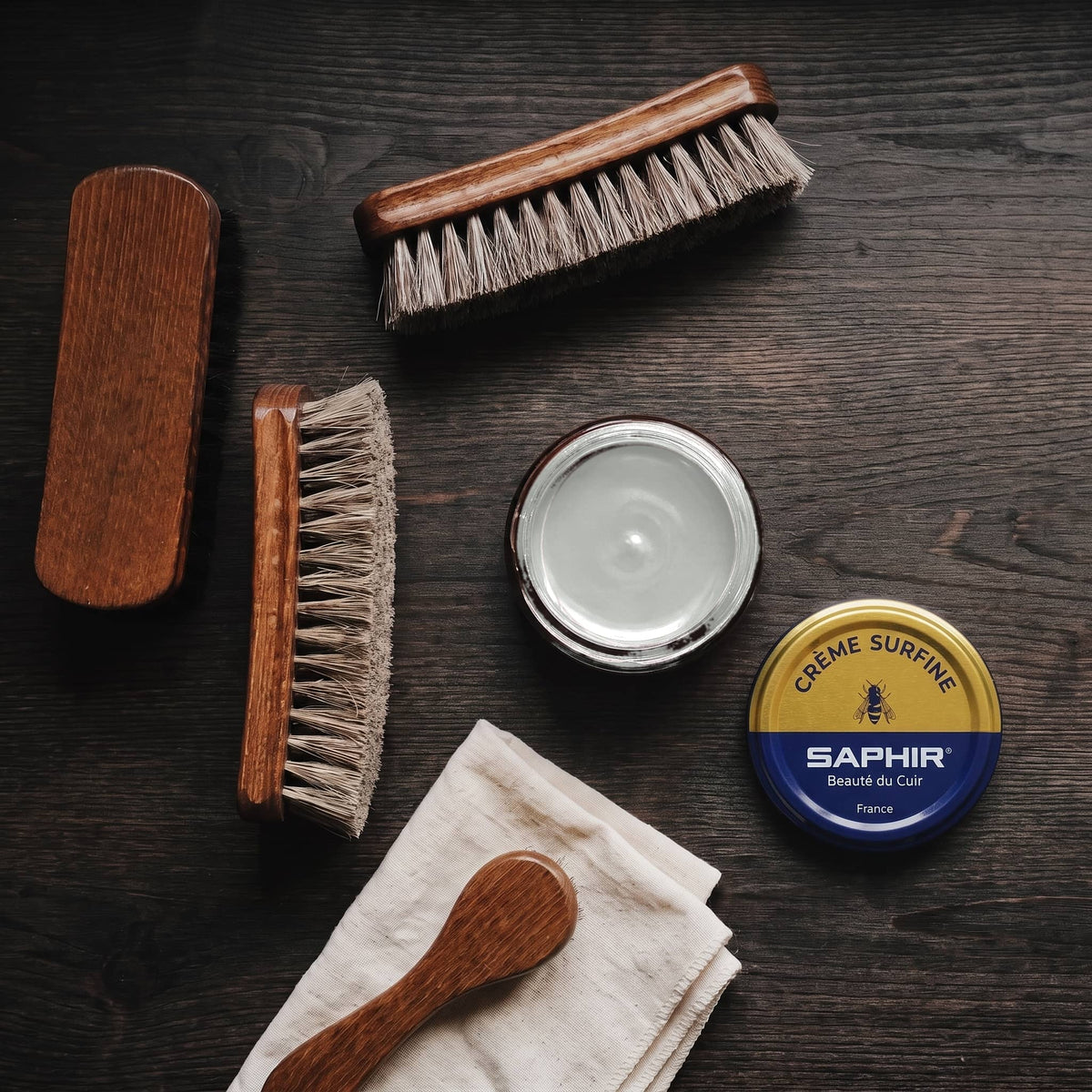 Crème Surfine Saphir Gris clair en pot ouvert, avec des brosses en crin et une chamoisine, vue de dessus