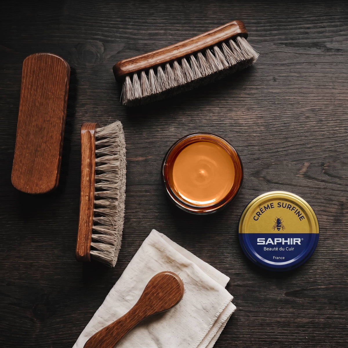 Crème Surfine Saphir Marron clair en pot ouvert, avec des brosses en crin et une chamoisine, vue de dessus