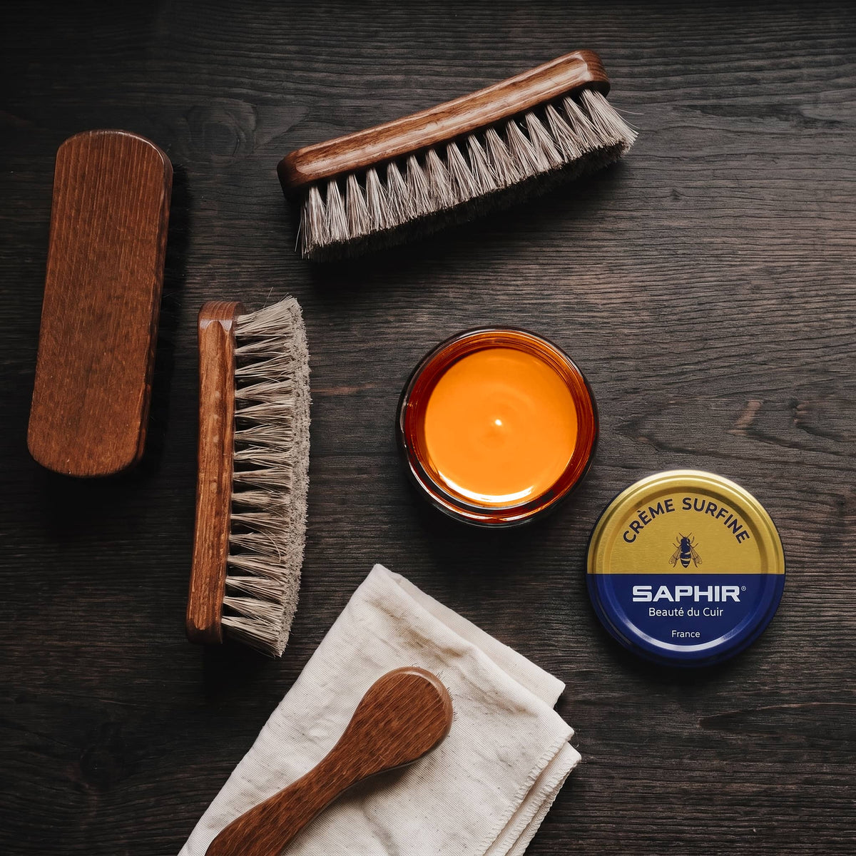 Crème Surfine Saphir Orange en pot ouvert, avec des brosses en crin et une chamoisine, vue de dessus