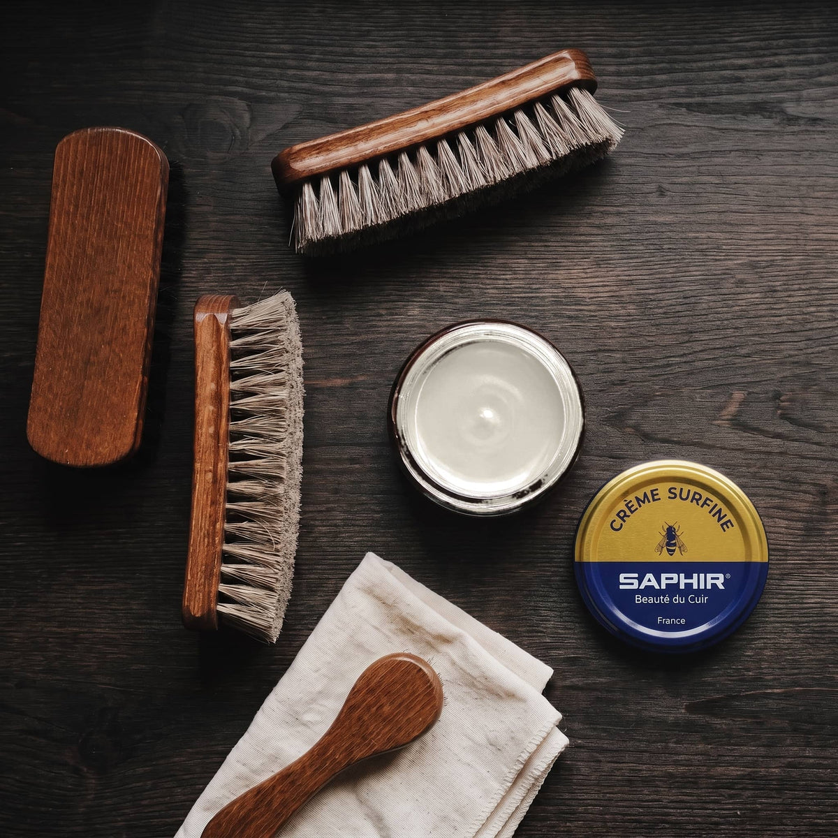 Crème Surfine Saphir Platine en pot ouvert, avec des brosses en crin et une chamoisine, vue de dessus