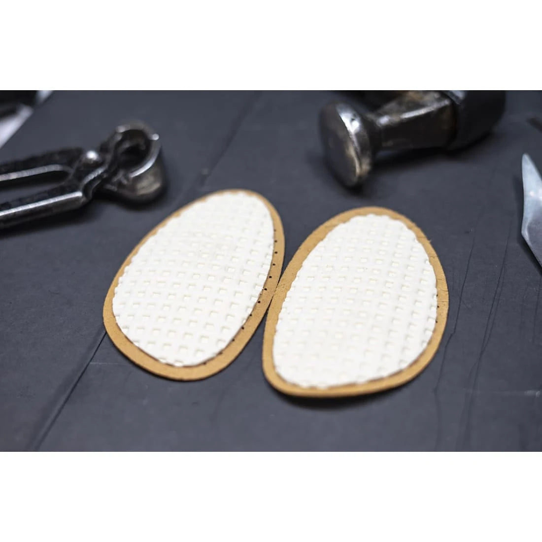 Deux demi-semelles retournées côté mousse, sur l’établi.