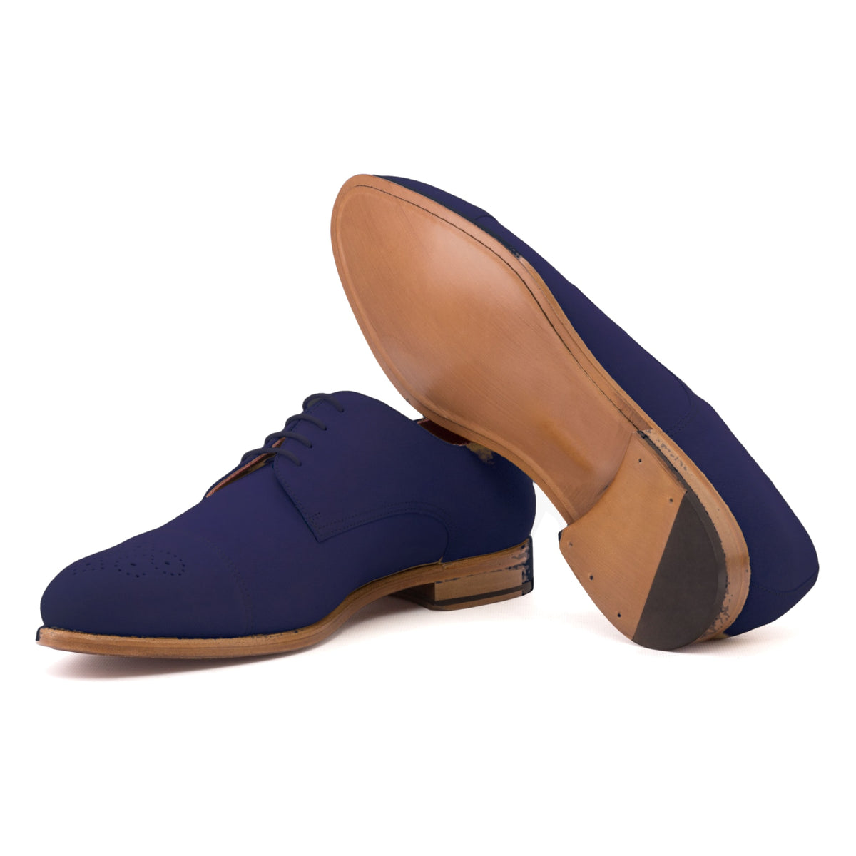Derby bout droit fleuri en daim de chevreau bleu marine, semelle cuir : une chaussure debout, l’autre couchée montre sa semelle