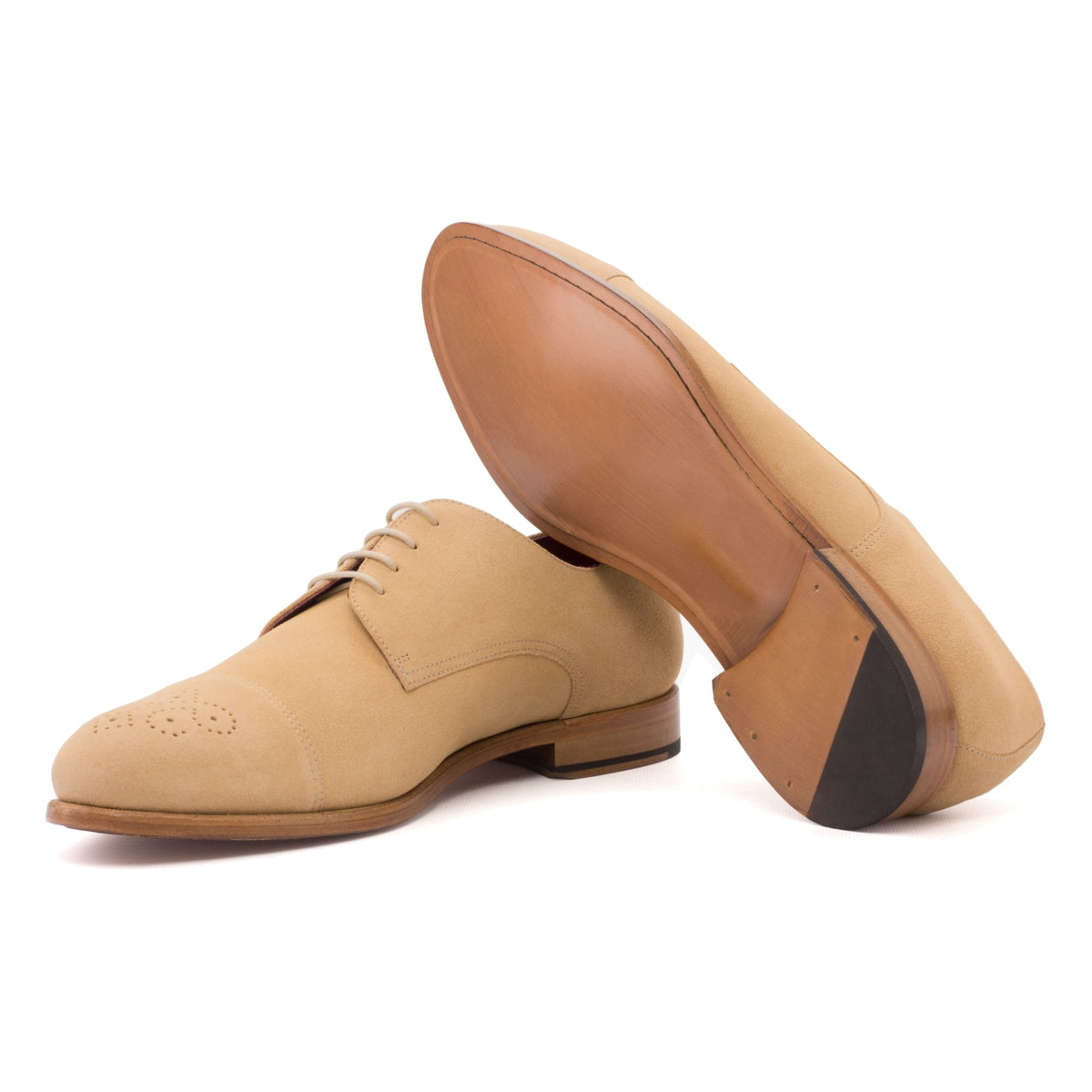 Derby bout droit fleuri en daim de chevreau camel, semelle cuir : une chaussure debout, l’autre couchée montre sa semelle