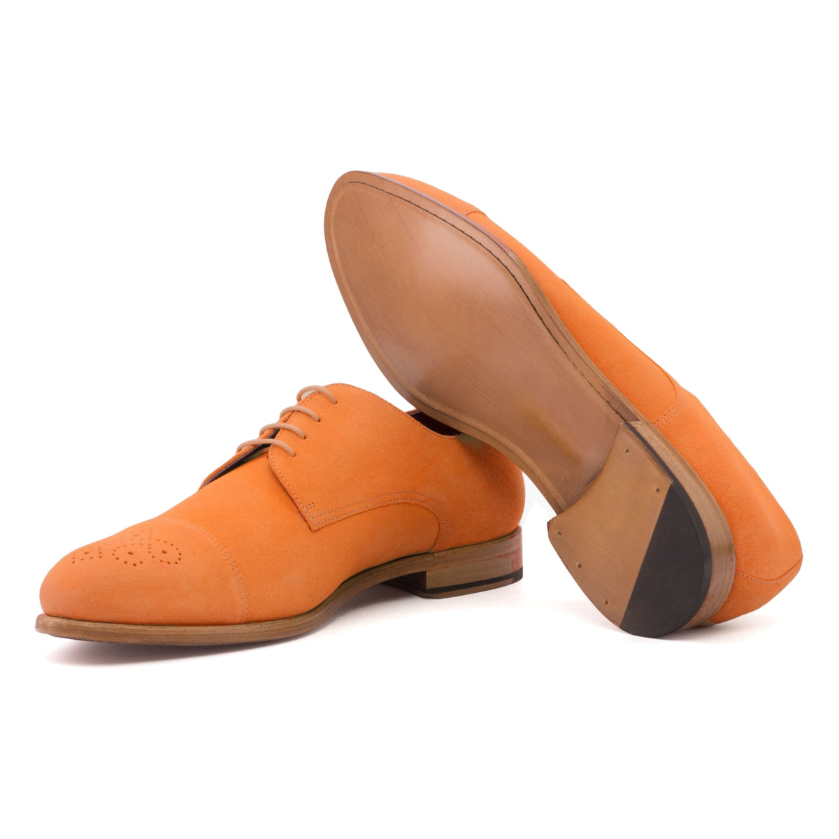 Derby bout droit fleuri en daim de chevreau orange, semelle cuir : une chaussure debout, l’autre couchée montre sa semelle