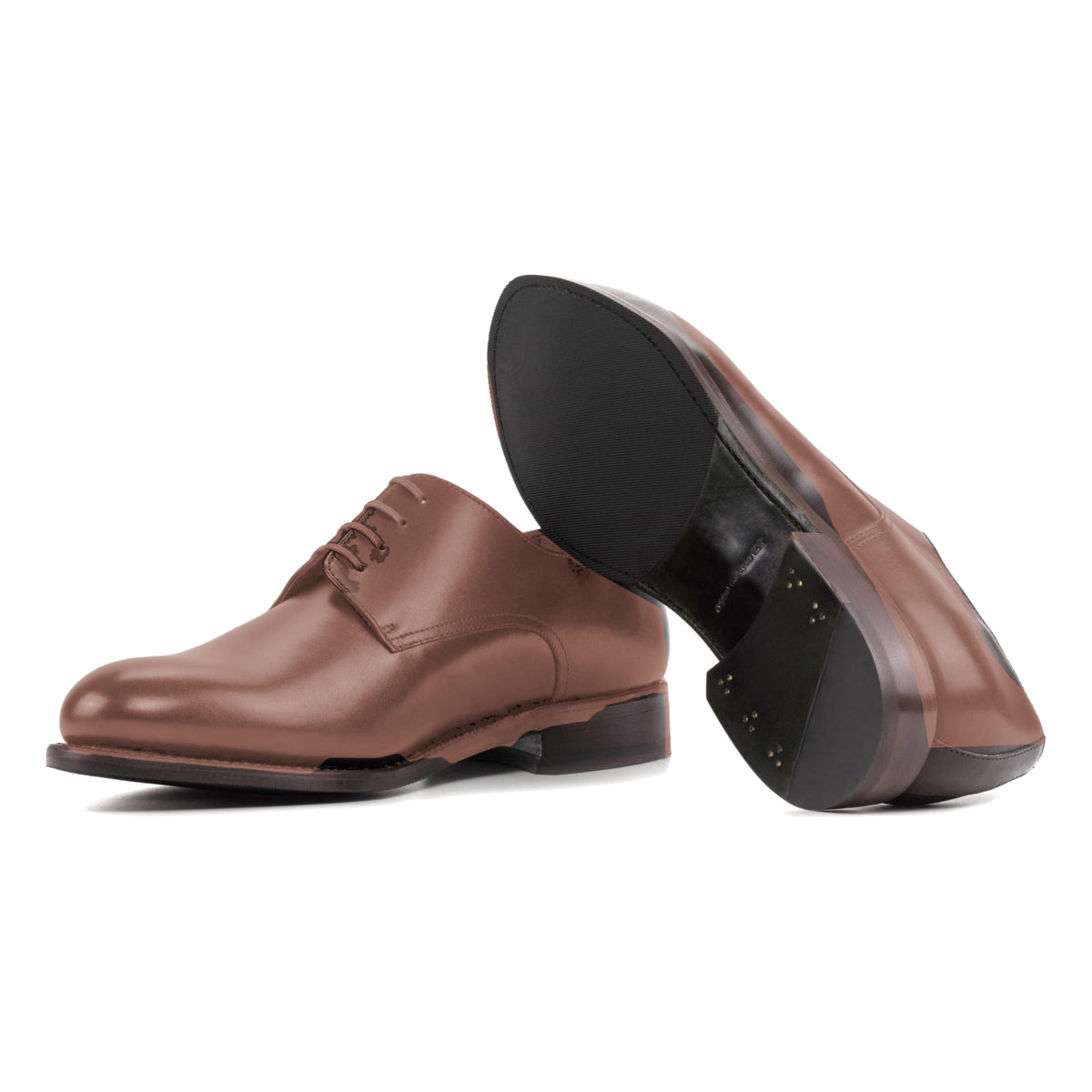 Derby en cuir teinté main marron moyen, semelle cuir et patin : une chaussure debout, l’autre couchée montre sa semelle