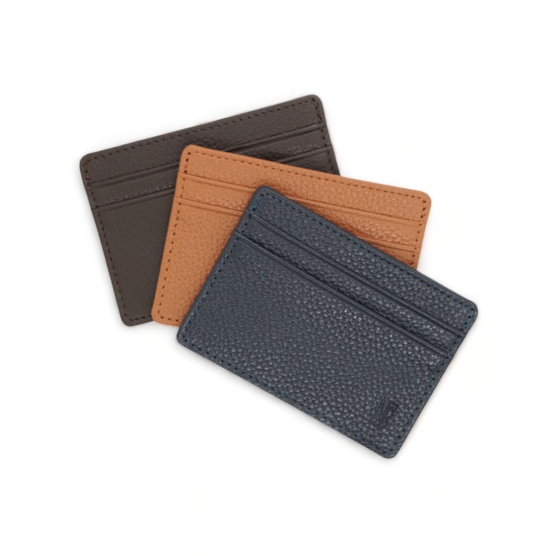 Les trois porte-cartes en cuir grainé posés en éventail : marron foncé, gold et bleu marine