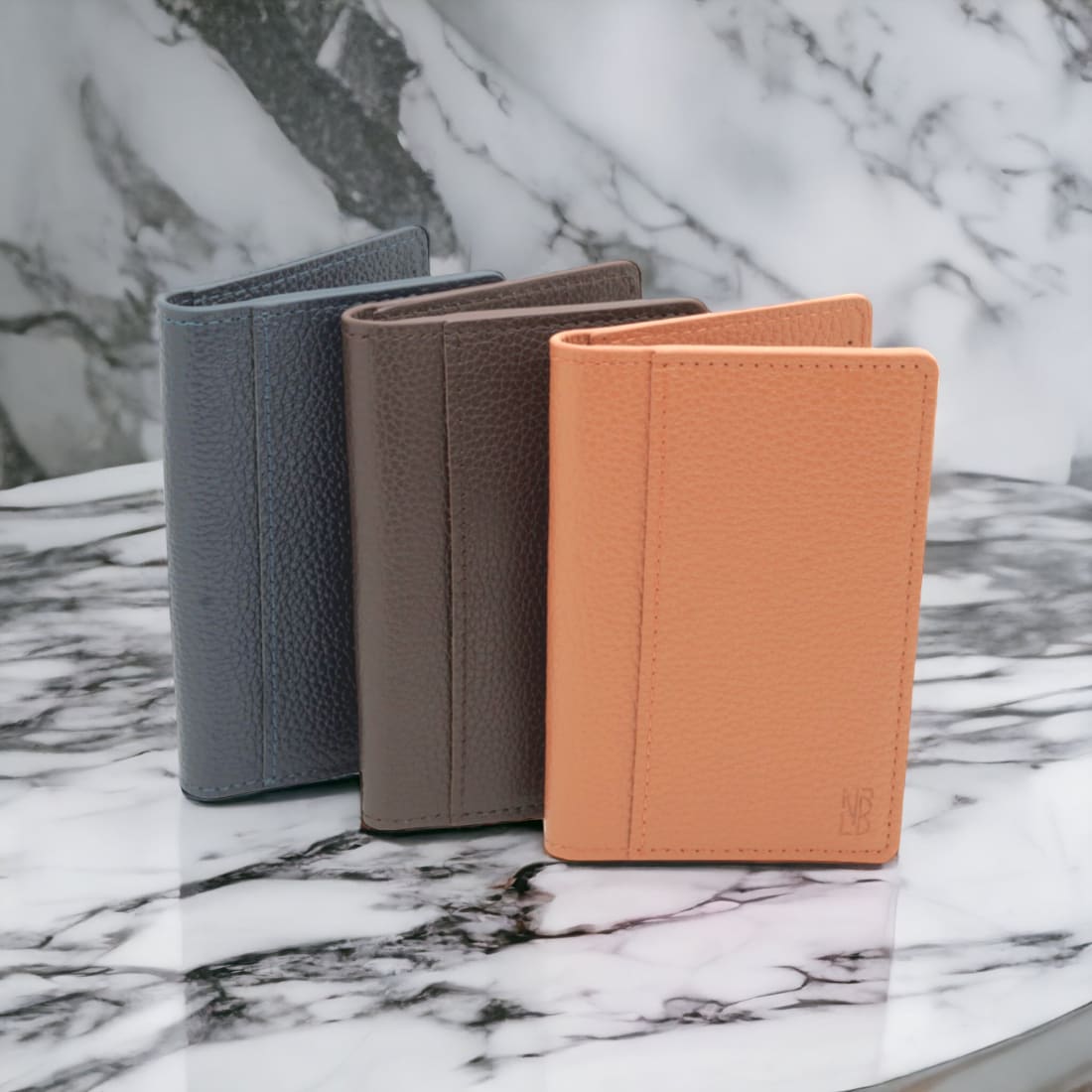 Les trois portefeuilles verticaux en cuir grainé sur un plateau de marbre