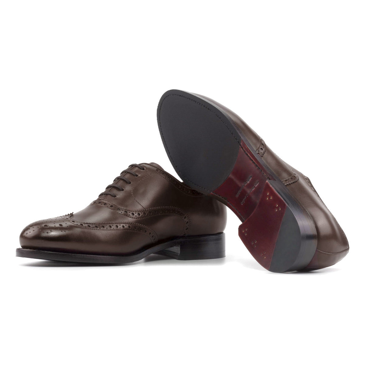 Richelieu fleuri en cuir marron moyen, semelle cuir et patin : une chaussure debout, l’autre couchée montre sa semelle