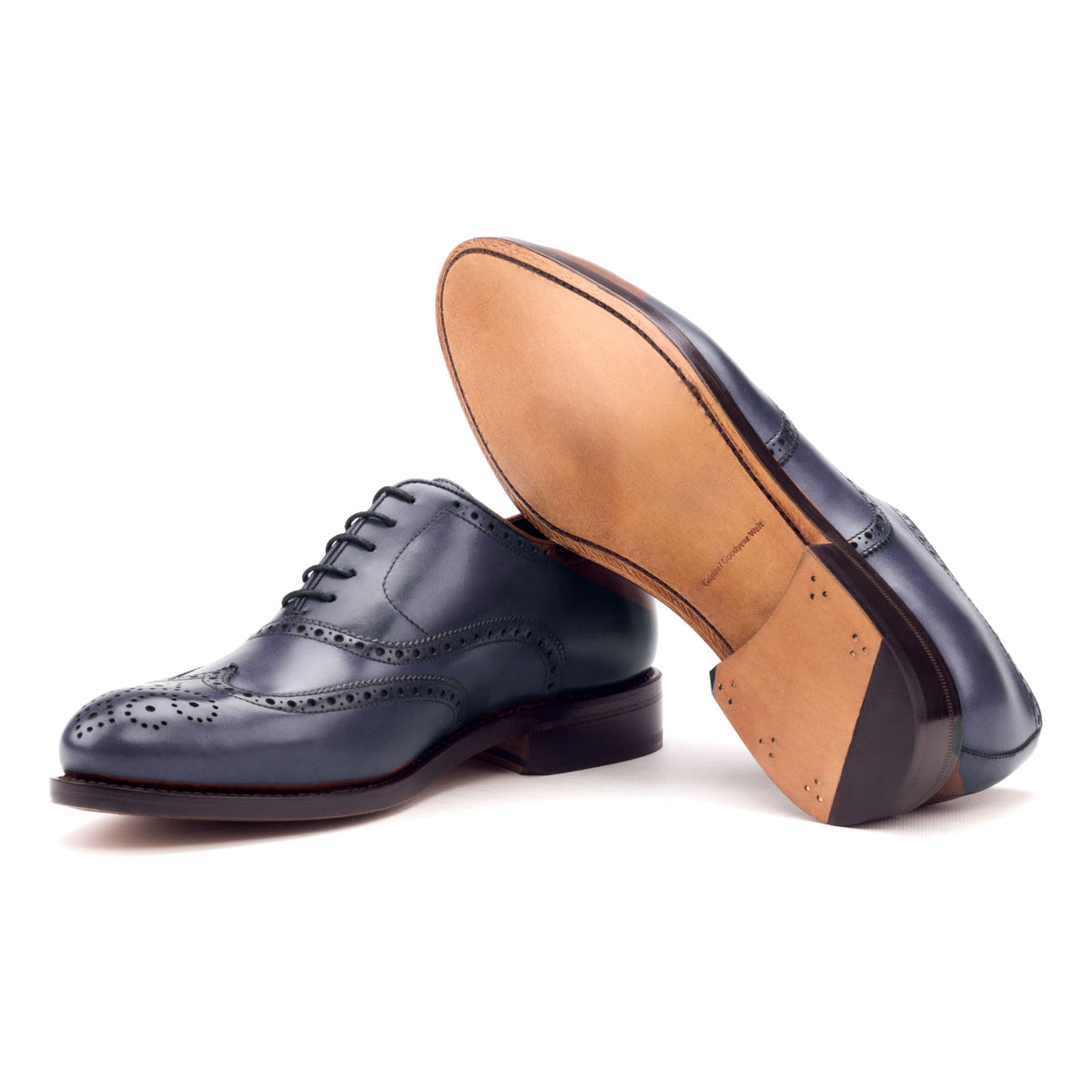 Richelieu fleuri en cuir teinté main bleu pétrole, semelle cuir : une chaussure debout, l’autre couchée montre sa semelle