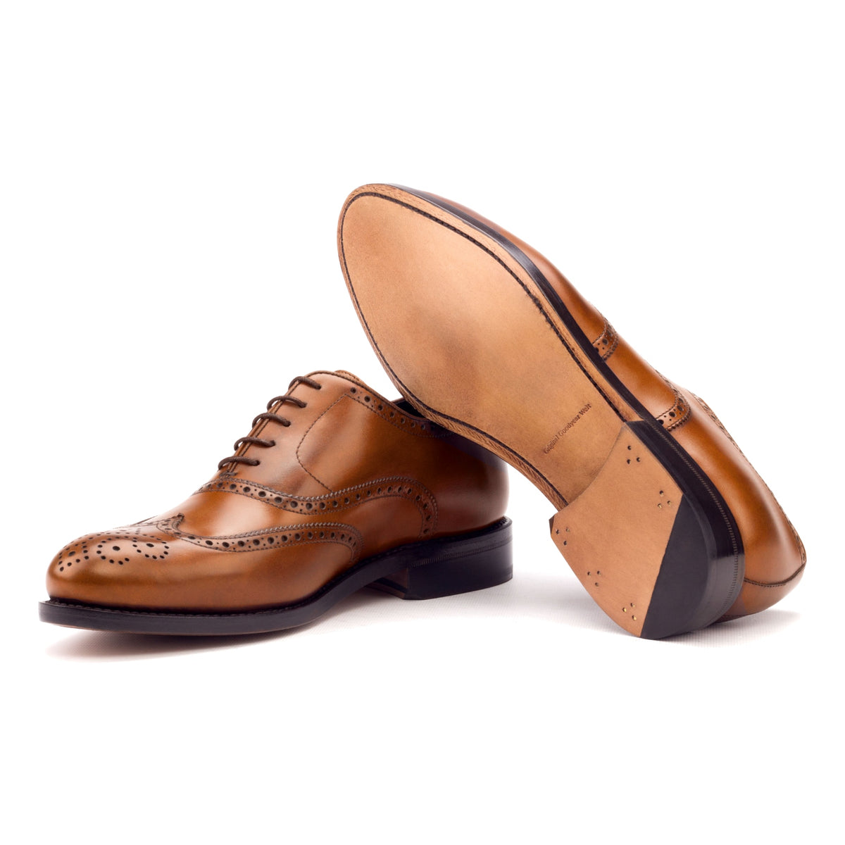 Richelieu fleuri en cuir teinté main cognac, semelle cuir : une chaussure debout, l’autre couchée montre sa semelle