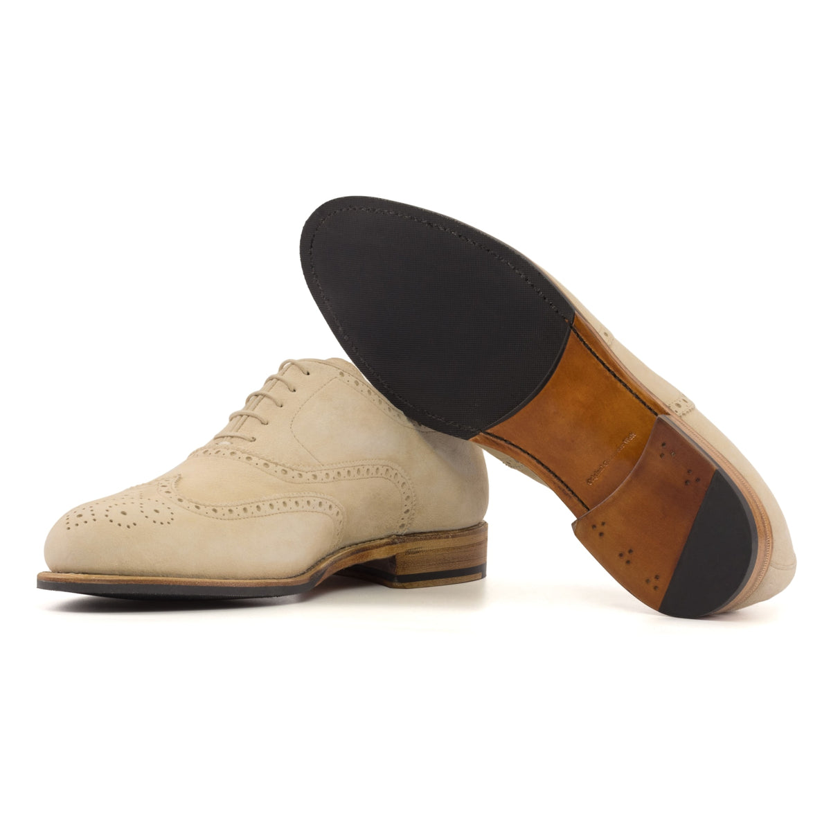 Richelieu fleuri en daim de chevreau beige, semelle cuir et patin : une chaussure debout, l’autre couchée montre sa semelle