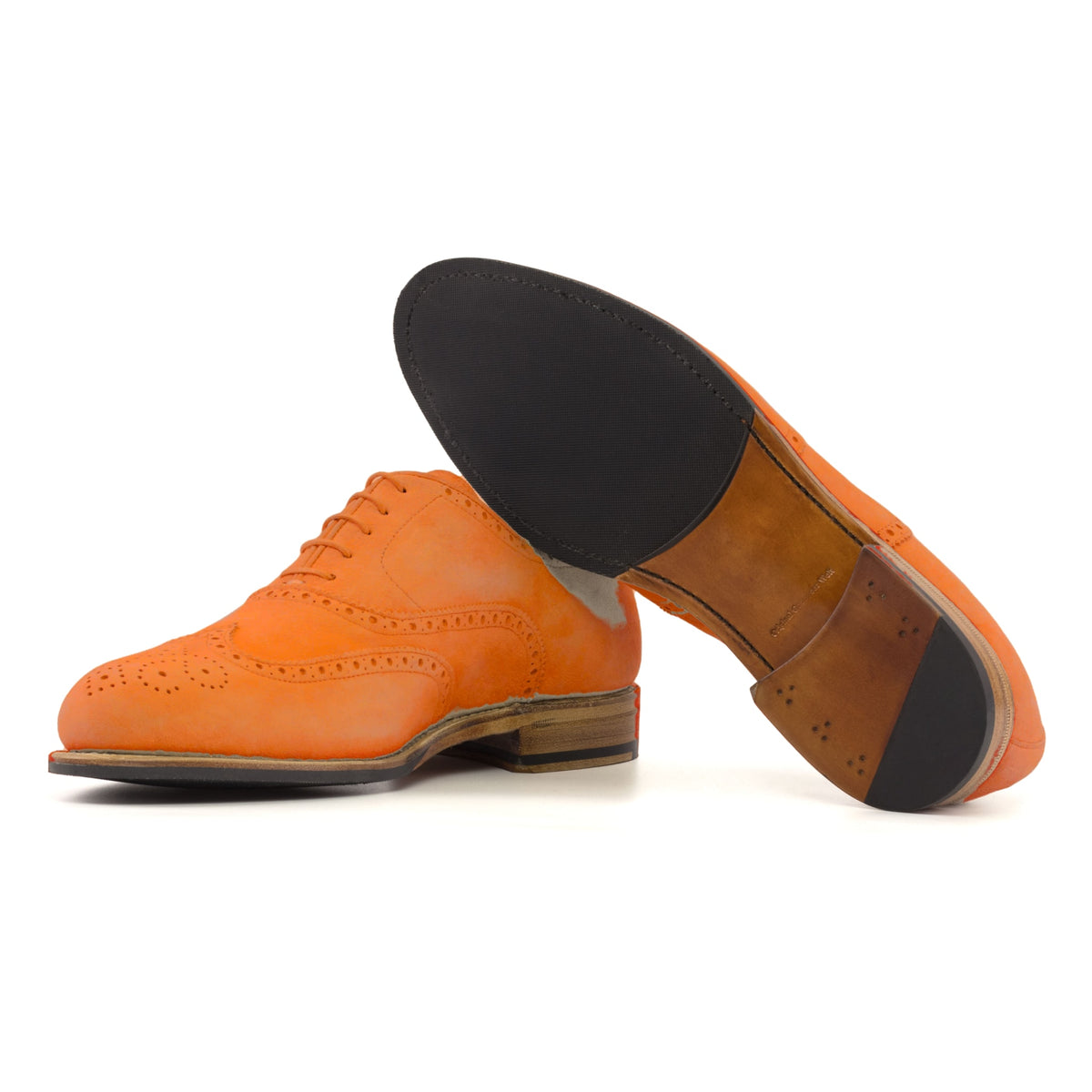 Richelieu fleuri en daim de chevreau orange, semelle cuir et patin : une chaussure debout, l’autre couchée montre sa semelle