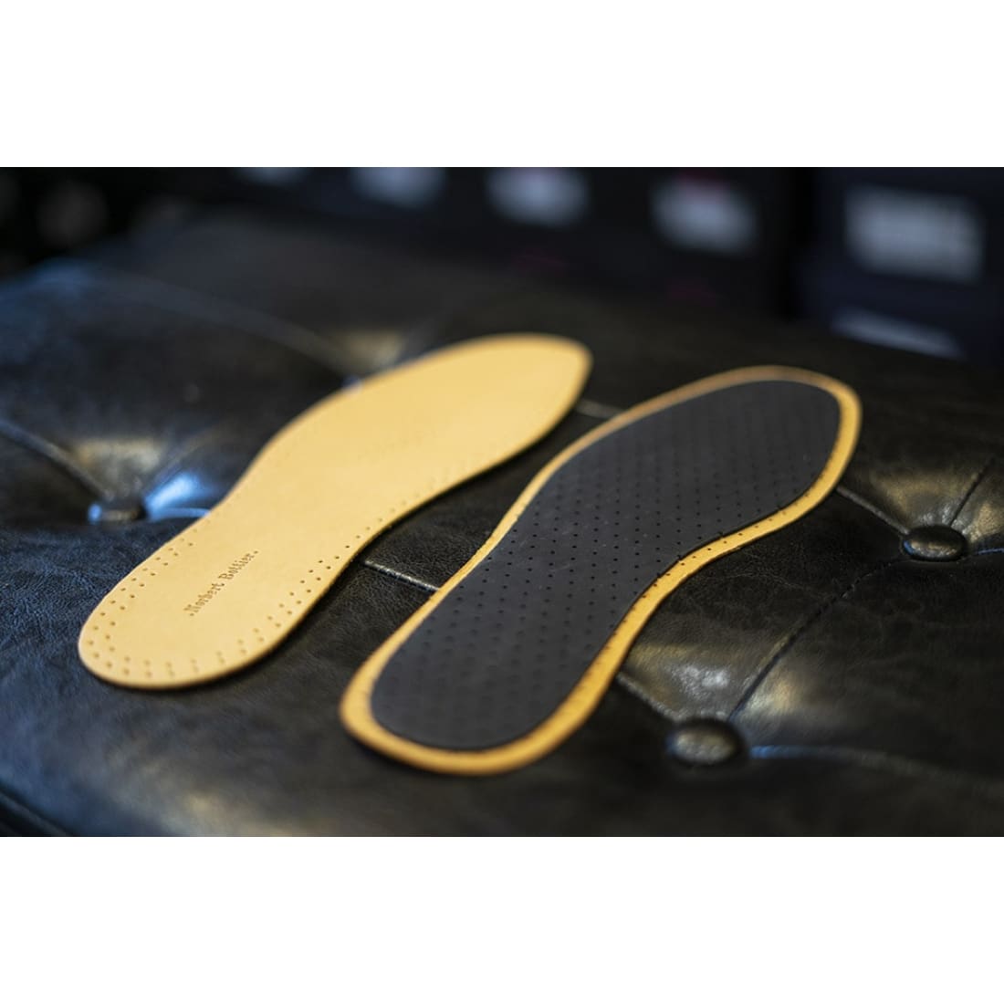 Une semelle côté cuir et une côté latex, posées sur un fauteuil capitonné.